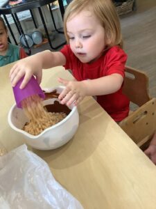 Preschool child mixing ingredients inside nursery. 